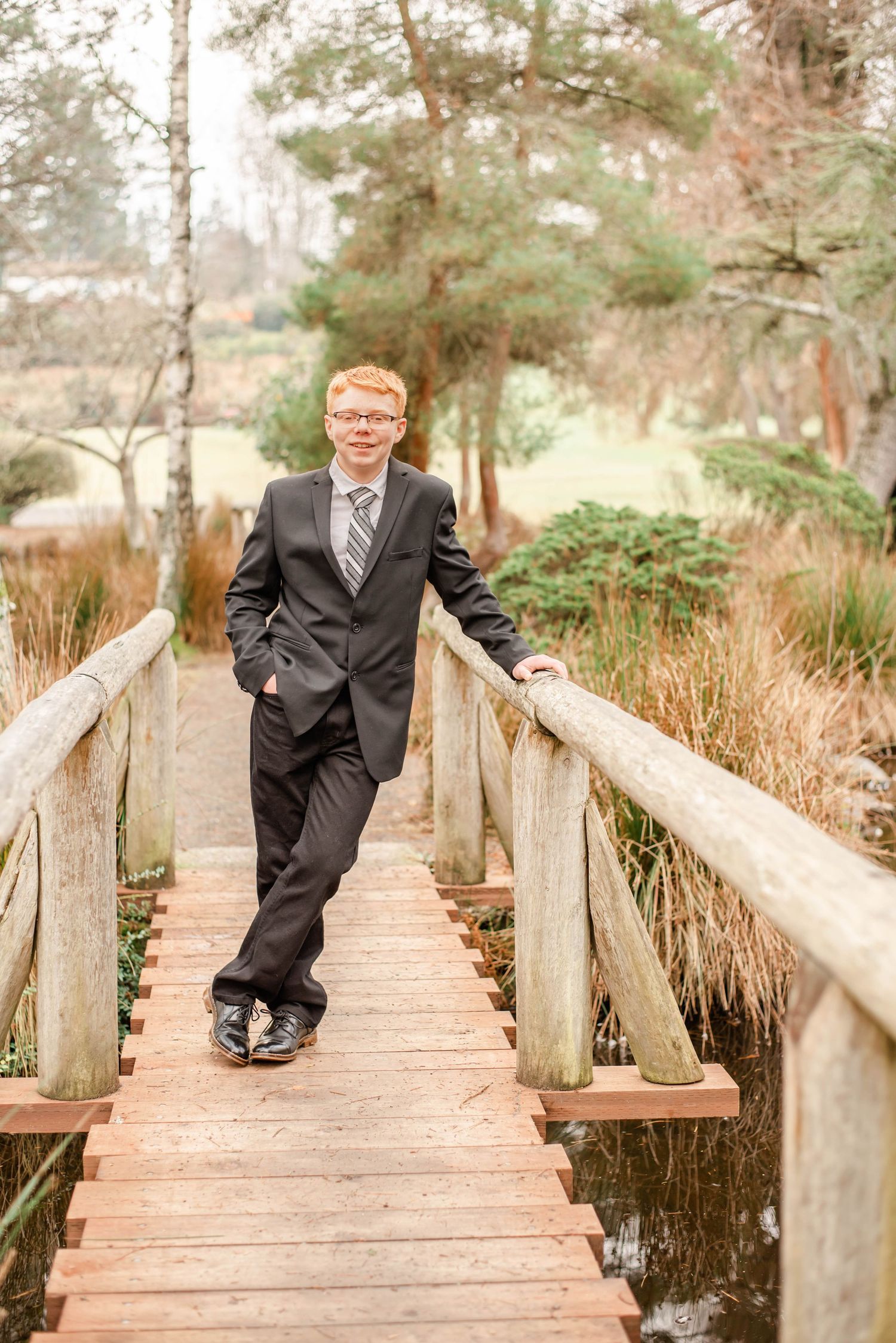 Outdoor formal portraits on rustic wooden bridge surrounded by natural scenery.