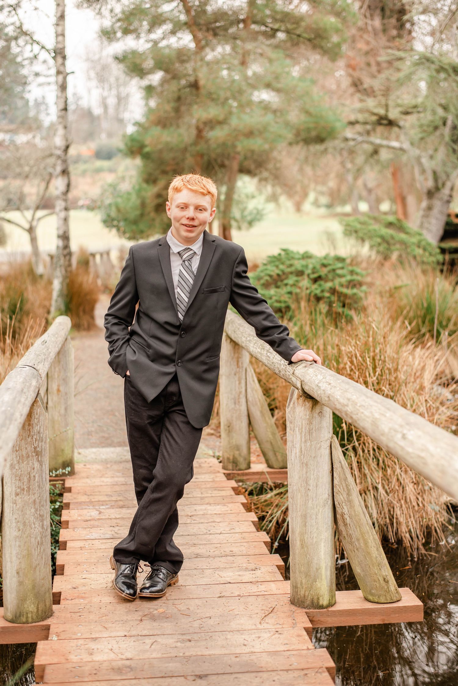 Candid shots on wooden boardwalk wearing formal black suit and striped tie.