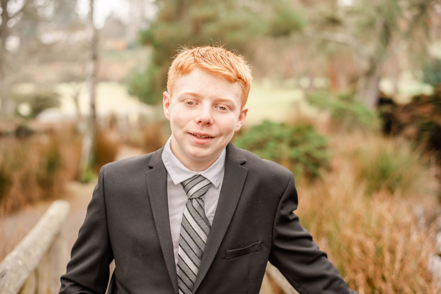 Professional portrait series in formal suit and tie against natural outdoor setting.