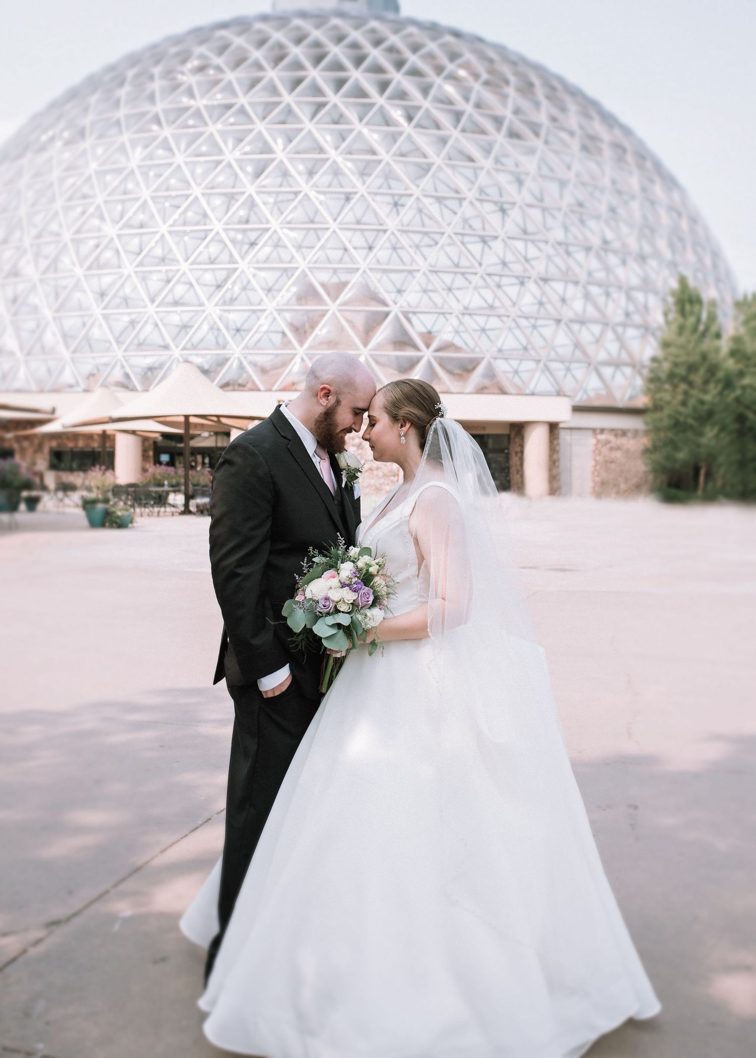 Portrait of Bride and Groom forehead to forehead in front of the Henry Doorly Zooly Zoo