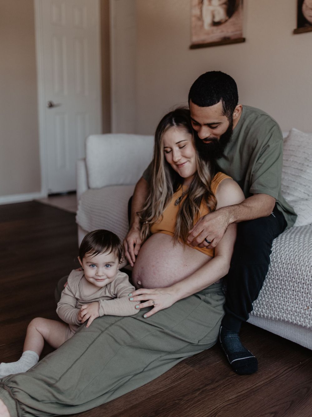 A family shares a loving moment on their couch during a maternity photoshoot.