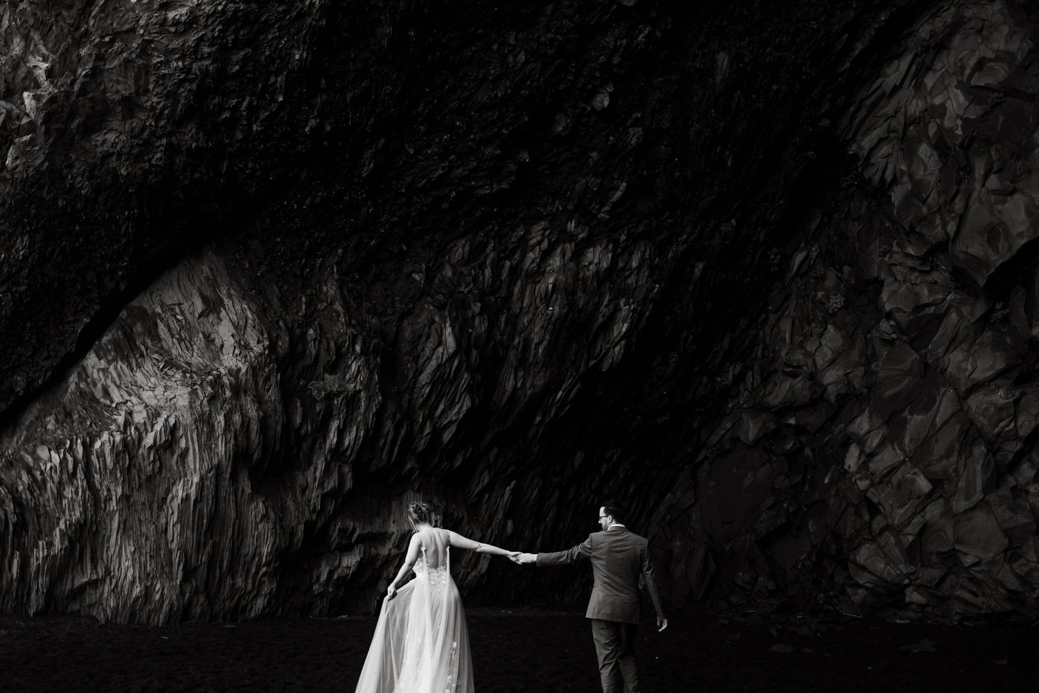 Dramatic black and white silhouette of a couple against a cave wall.