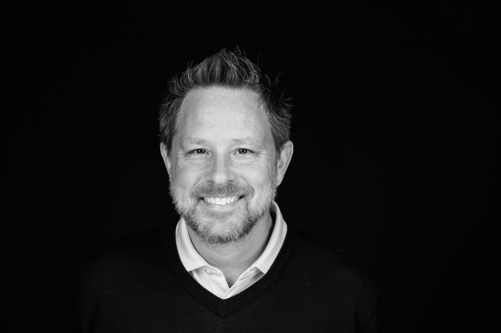 Black and white portrait against dark background with warm expression.
