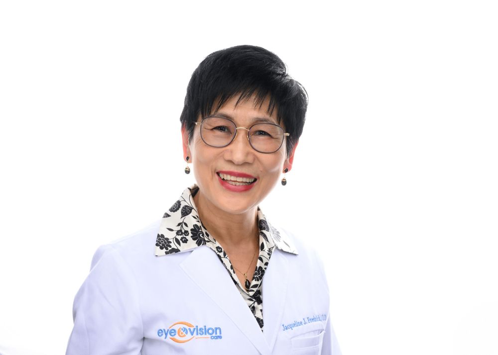 Healthcare professional in white coat and patterned shirt smiling at camera.