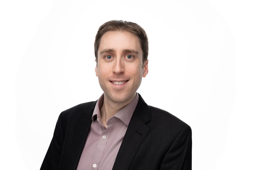 Professional business headshot against white background showing warm expression.