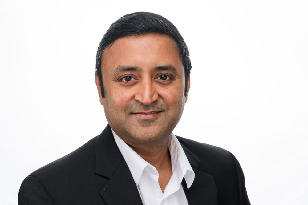 Professional headshot of someone in a business suit against a white background.