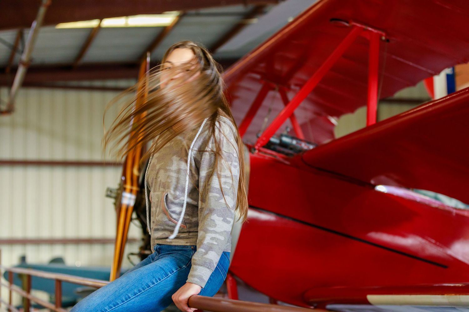 Artsy shot of girl whipping hair on a red biplane