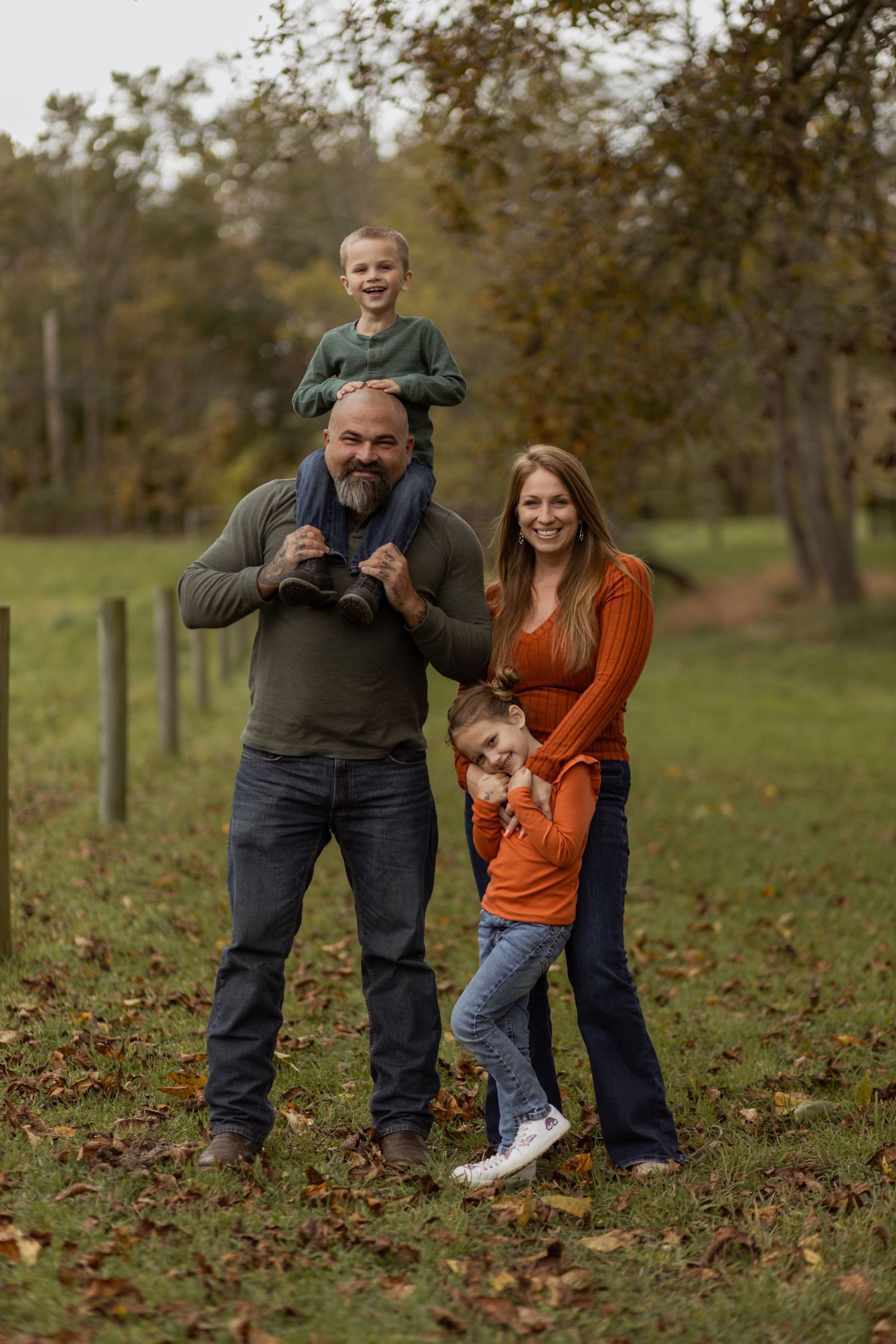 Family plays together in fallen autumn leaves during outdoor photoshoot.