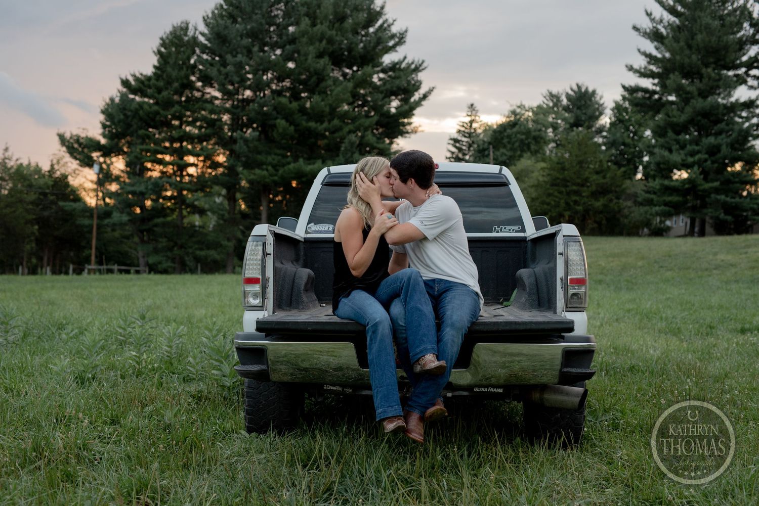 A romantic evening moment shared on the back of a pickup truck at sunset.