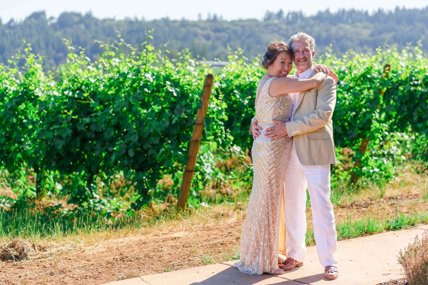 bride and groom hug by a vineyard