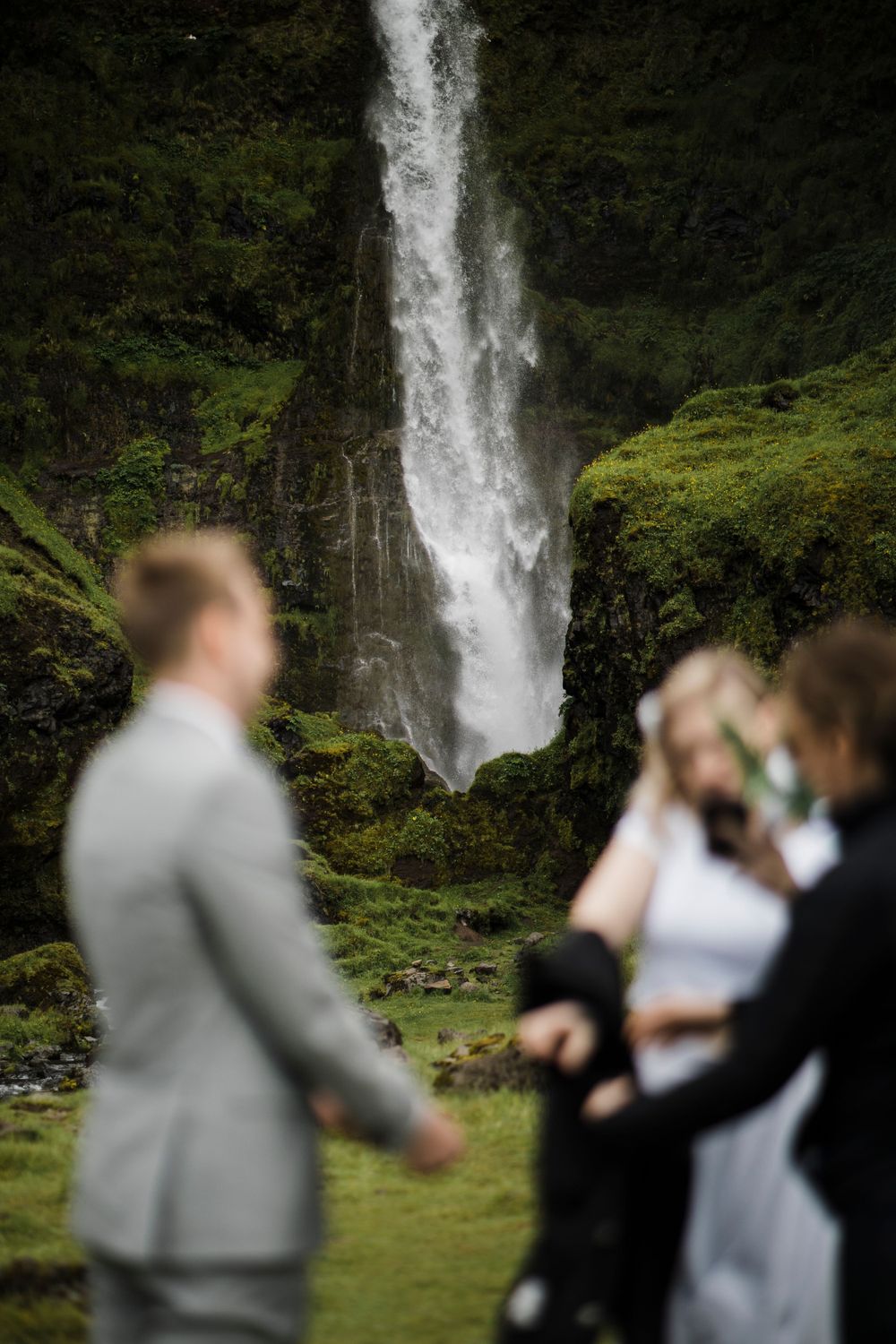 Majestic waterfall cascading down moss-covered cliffs during outdoor wedding ceremony.