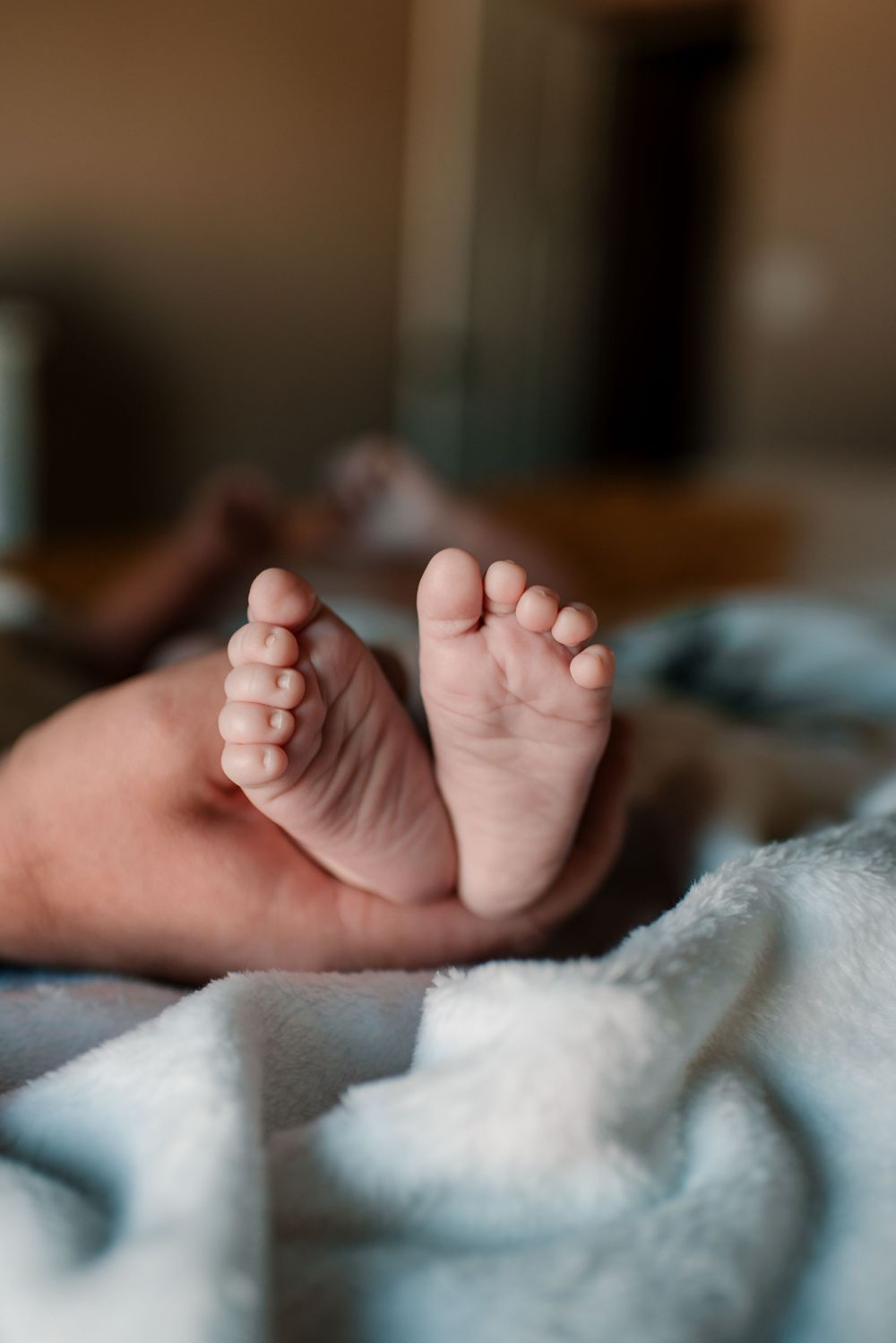 Close-up of tiny baby feet against soft white blankets.