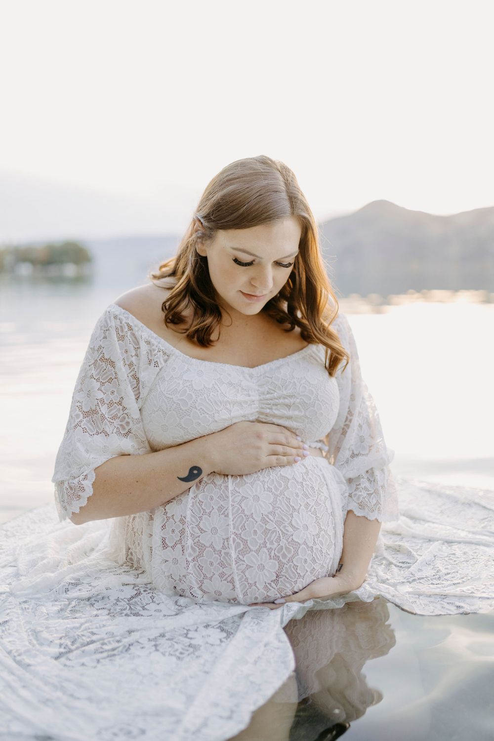 Ethereal waterfront maternity session featuring delicate white lace details and soft natural light.