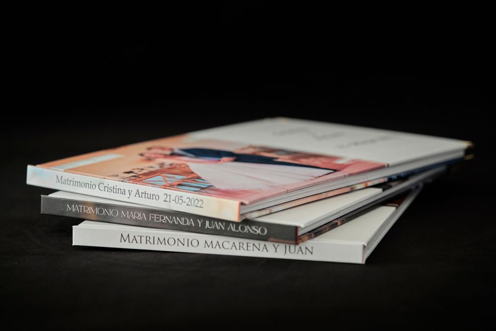 Stack of white photo albums or books photographed against dark background.
