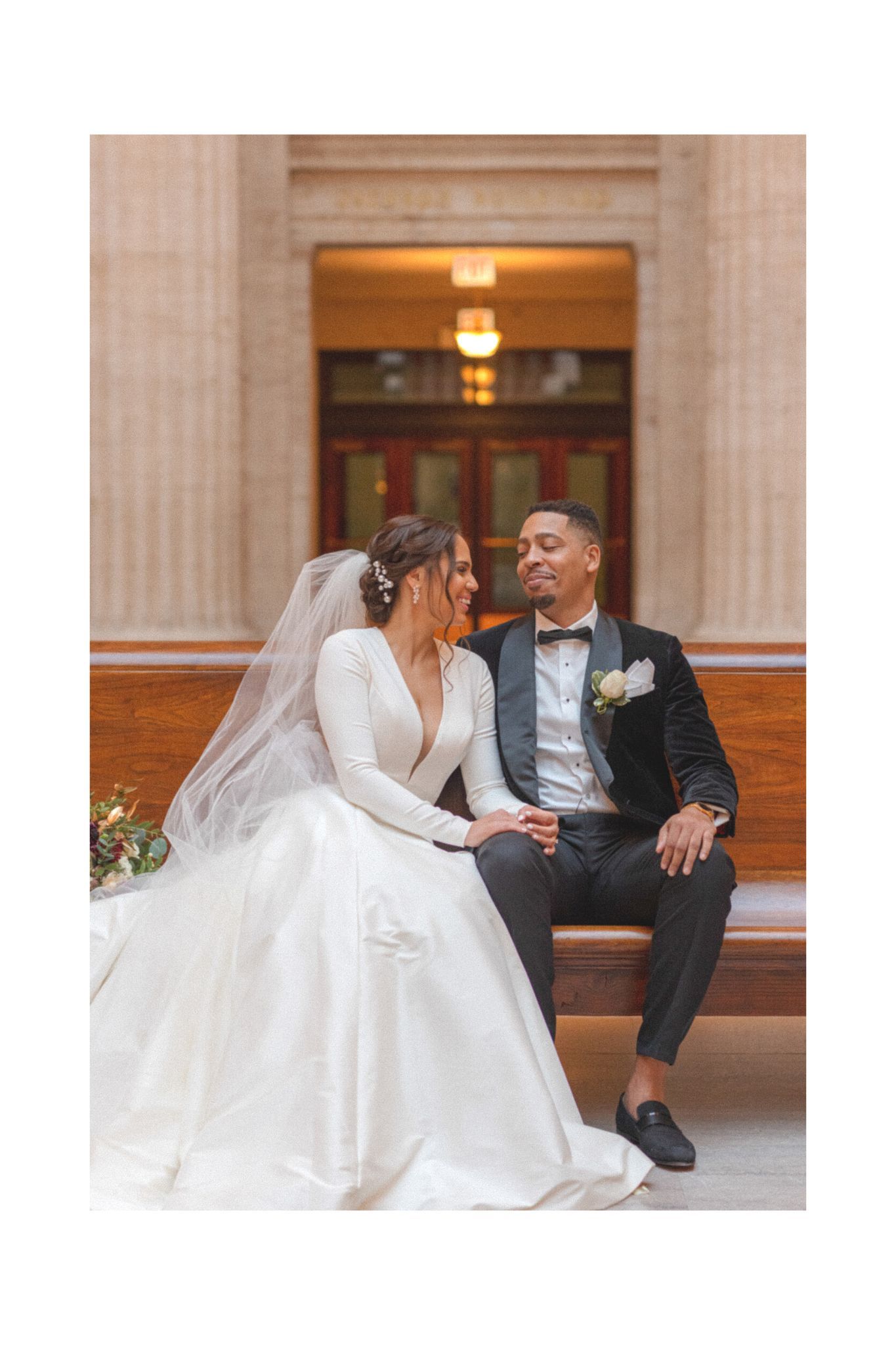 Wedding couple sharing intimate moment while seated in ornate architectural setting.