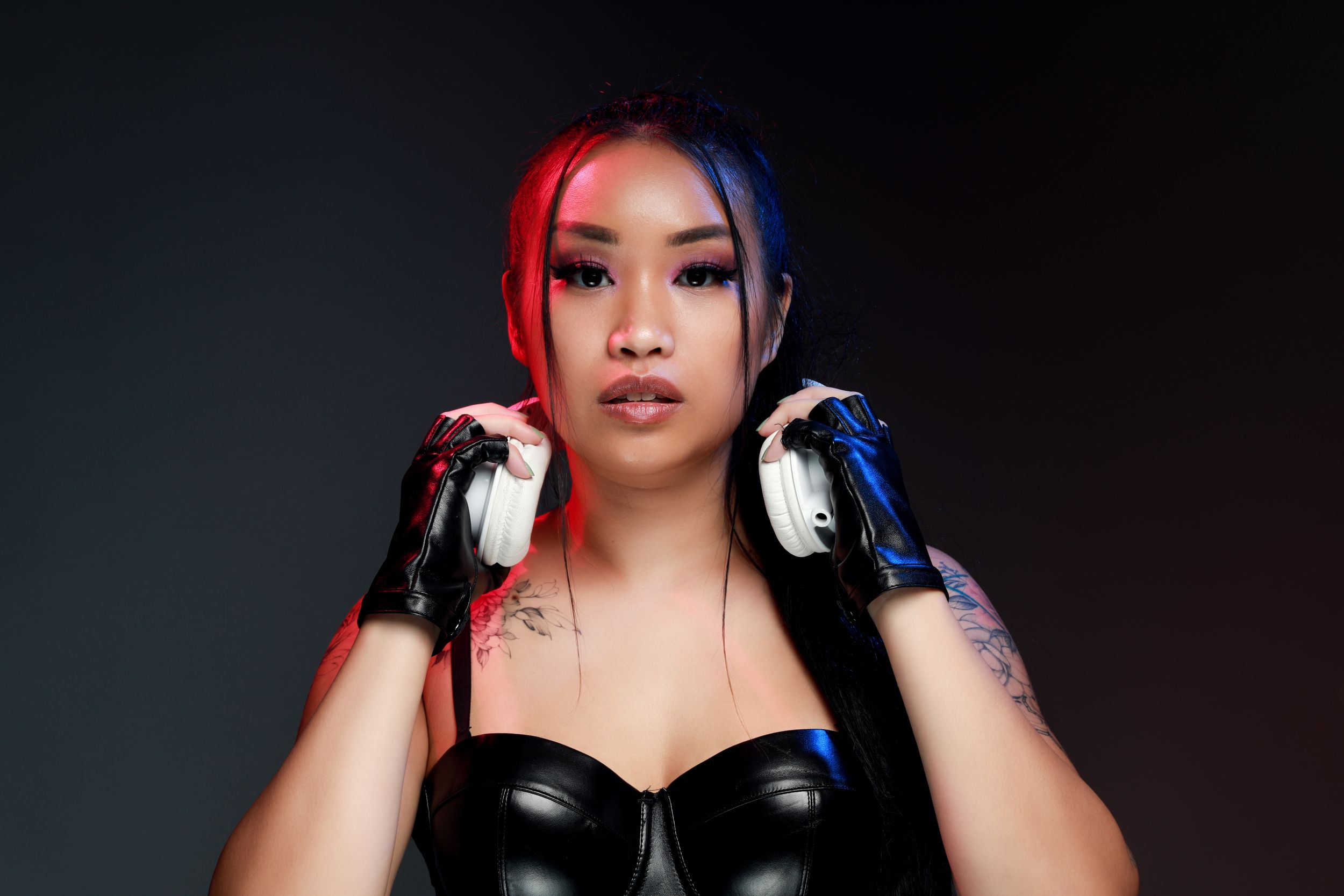 DJ portrait with red and blue split lighting wearing black leather outfit.