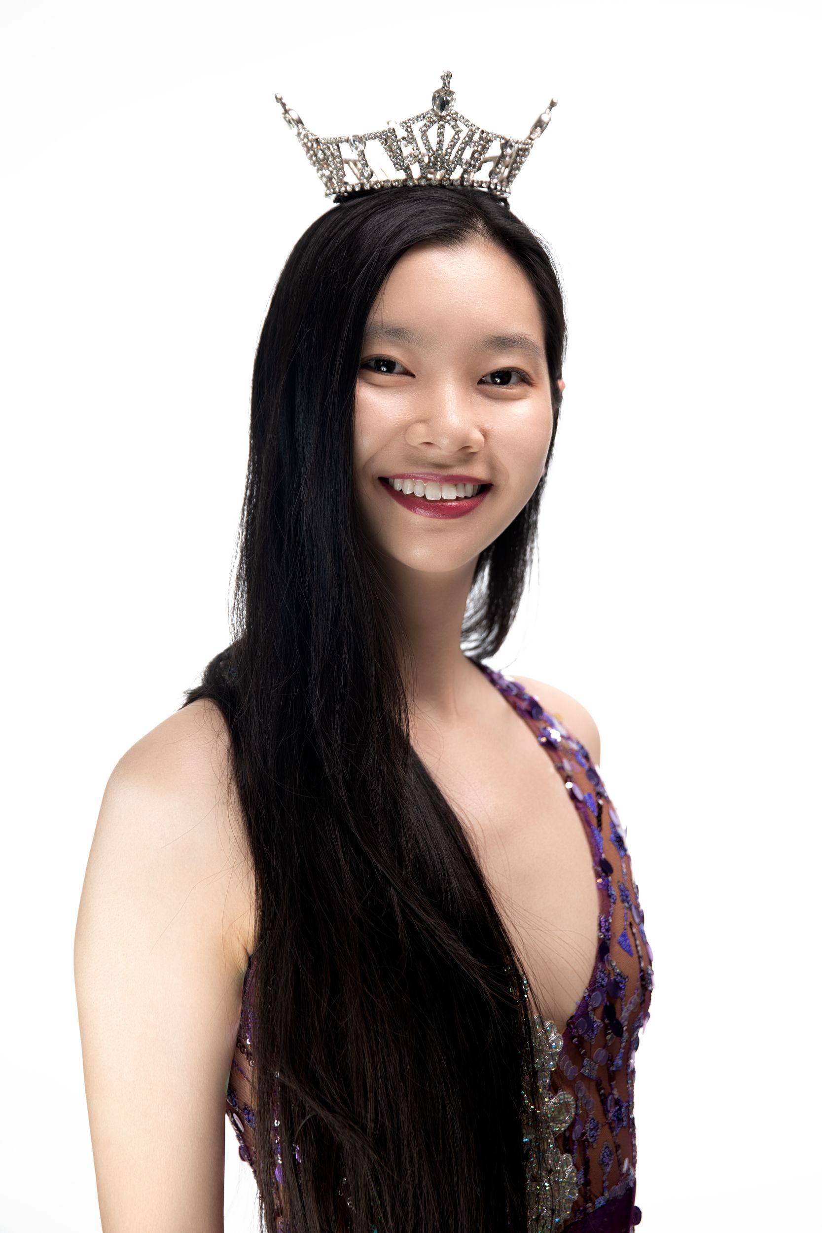 Portrait wearing sparkly crown and formal gown against white background.