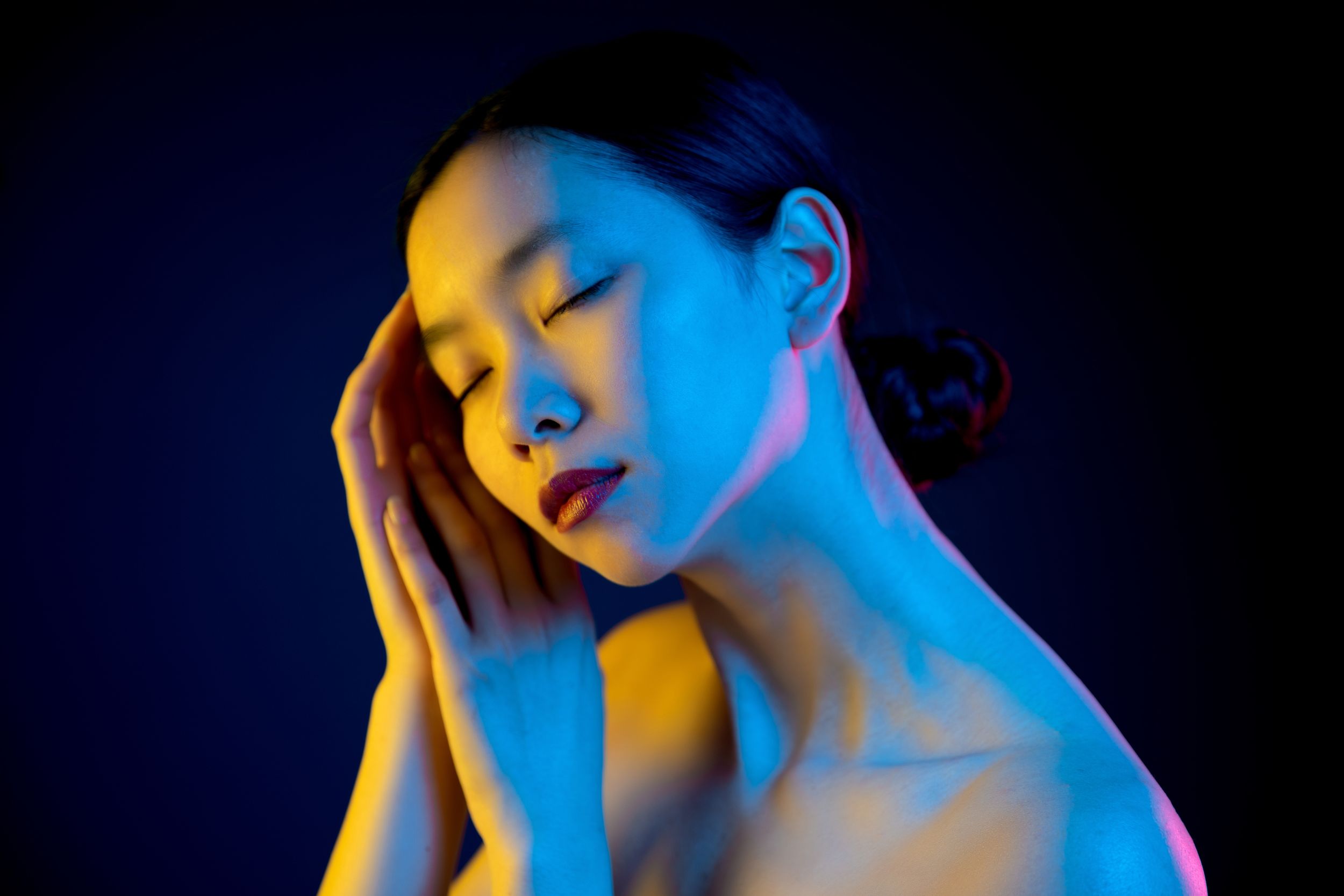 Artistic portrait with vibrant blue and orange lighting creating a dreamy mood in dark setting.