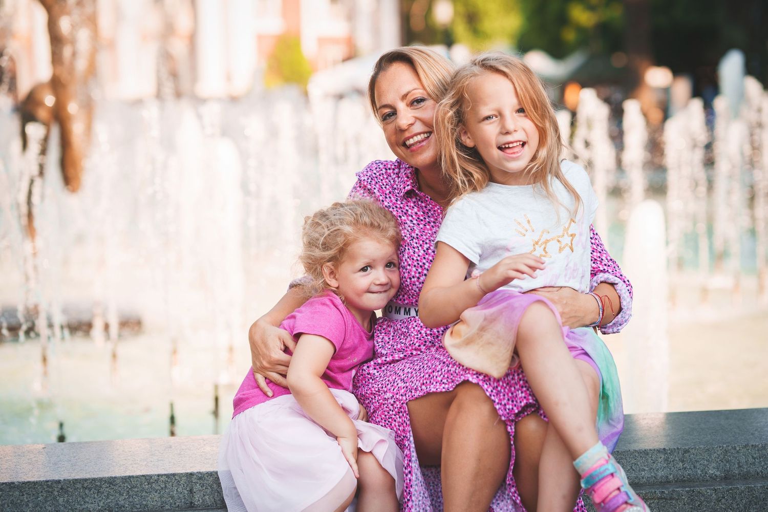 Family group sharing loving moment while sitting by outdoor fountain.