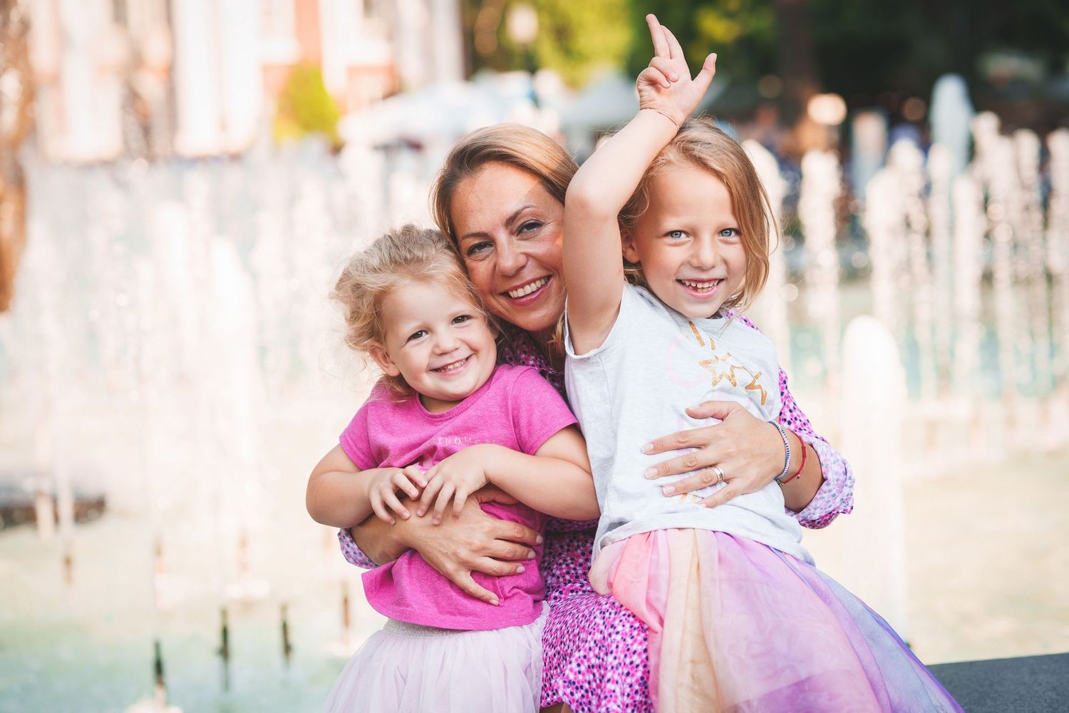 Joyful family moment captured by fountain with playful expressions.
