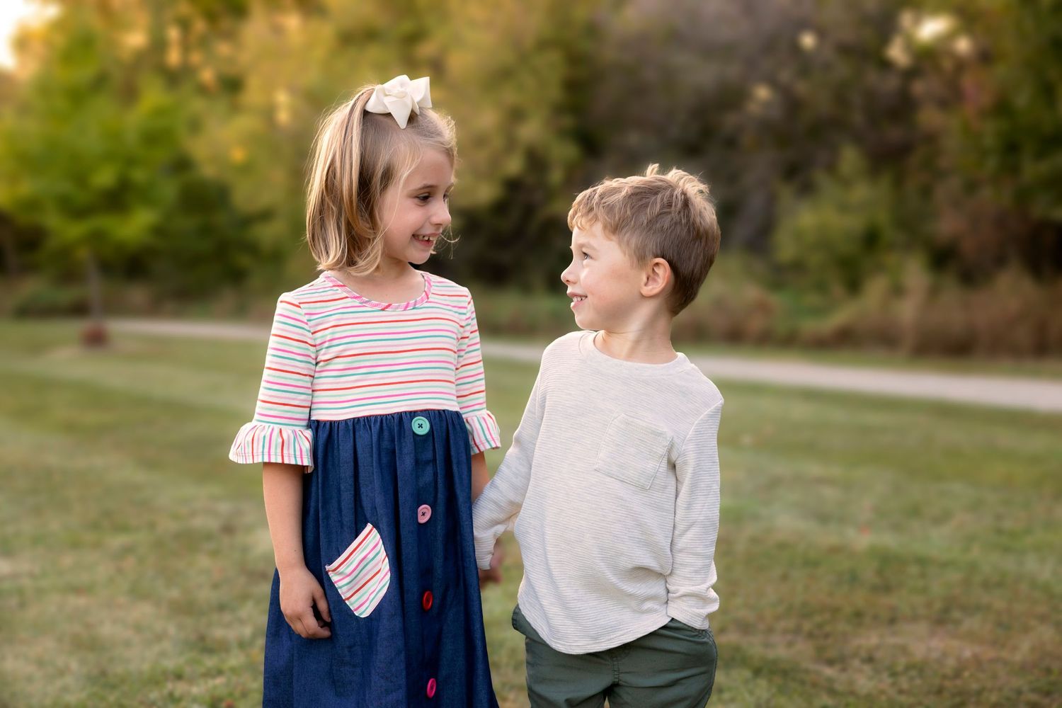 Two children share a laugh together outdoors during golden hour.