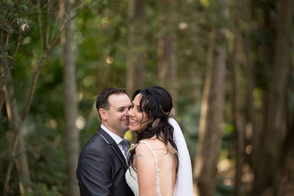 Romantic forest wedding portrait with couple embracing among trees.