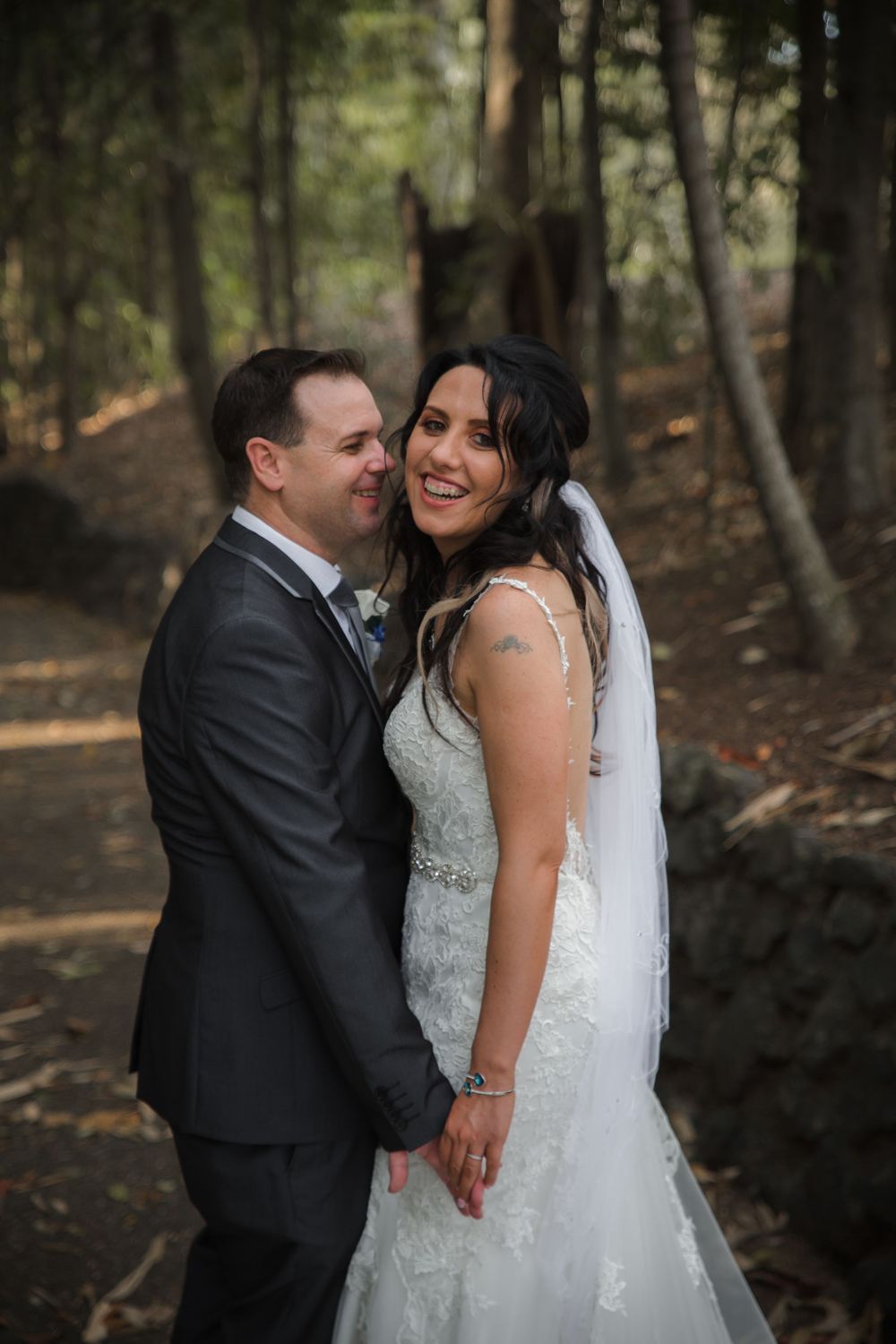 Beautiful wedding portrait of a couple sharing a joyful moment together in a wooded forest setting.