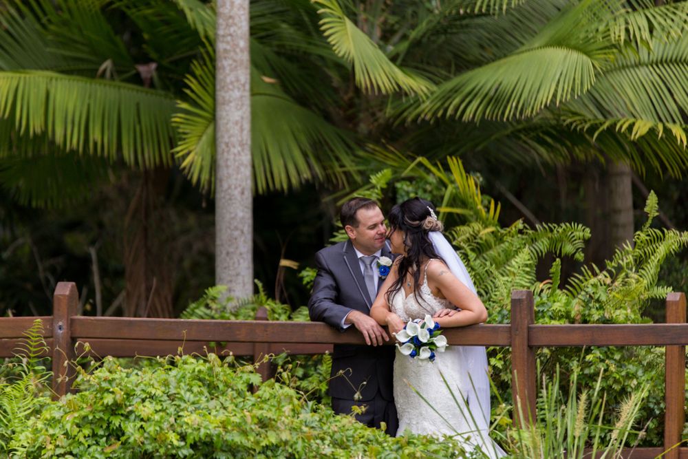 Intimate wedding moment captured in tropical garden setting with palm trees.