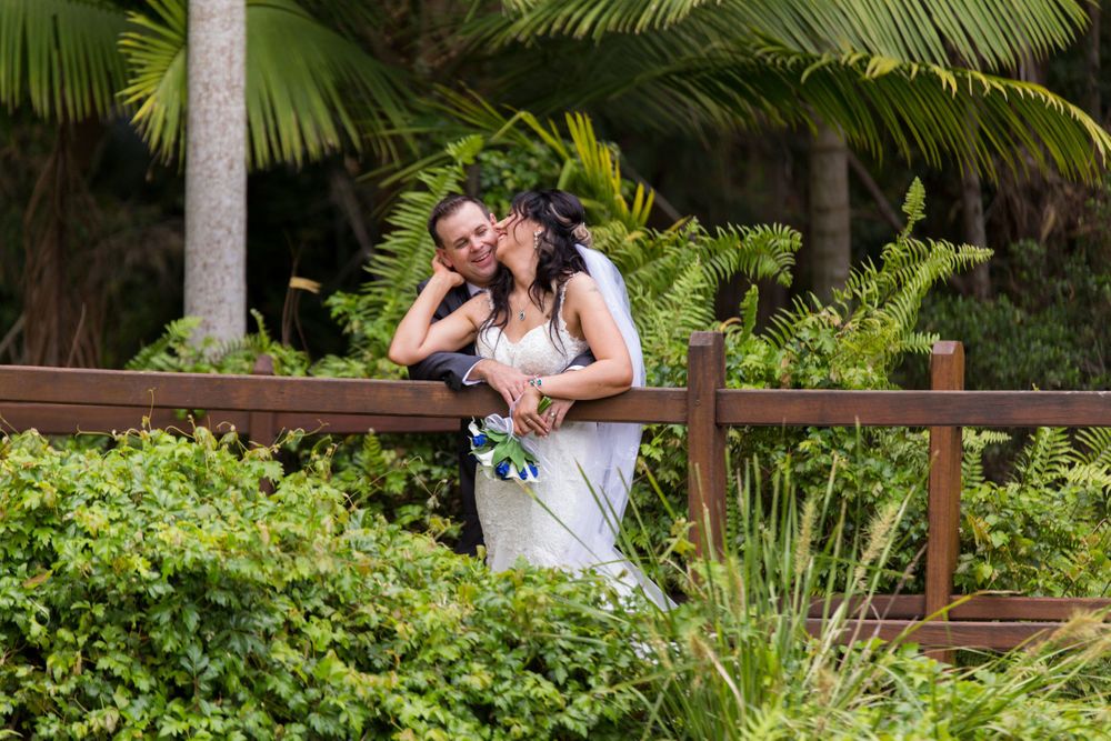 Tender wedding moment shared between couple in lush tropical garden setting.