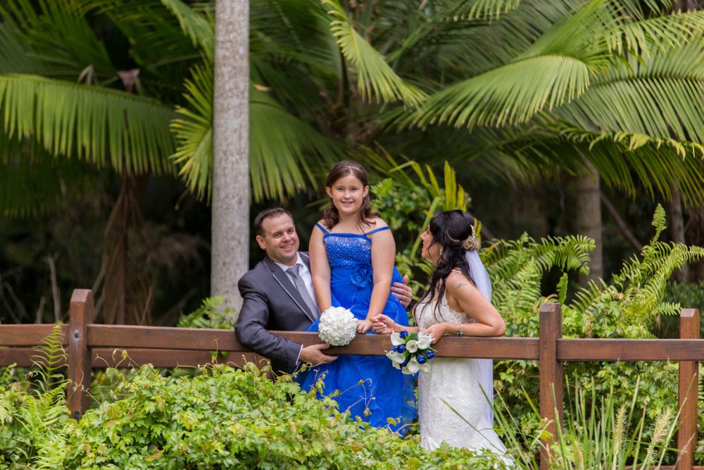 Wedding party poses together in vibrant tropical garden with palm trees.