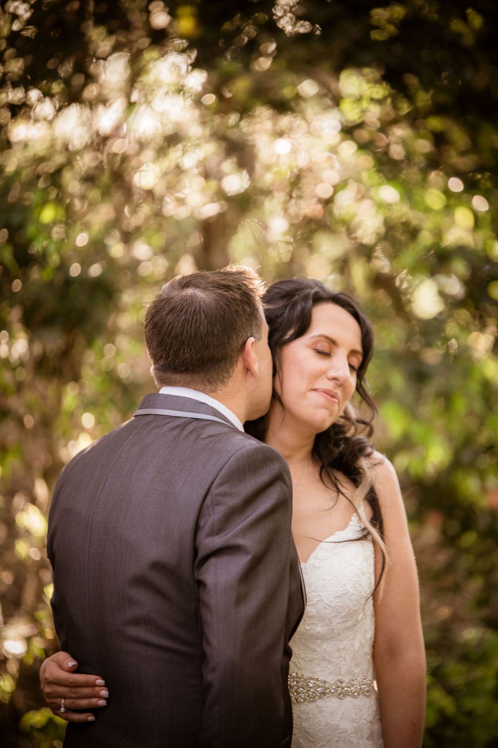 Wedding couple embracing in romantic garden setting with dreamy bokeh lighting effects.
