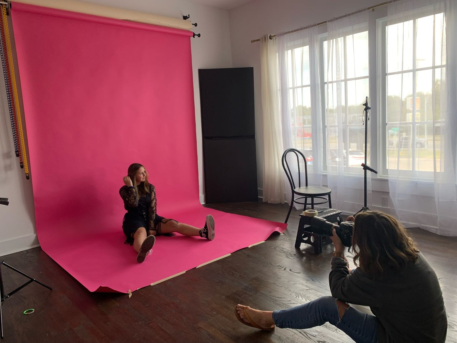 Behind the scenes photo shoot setup with pink backdrop and camera equipment.