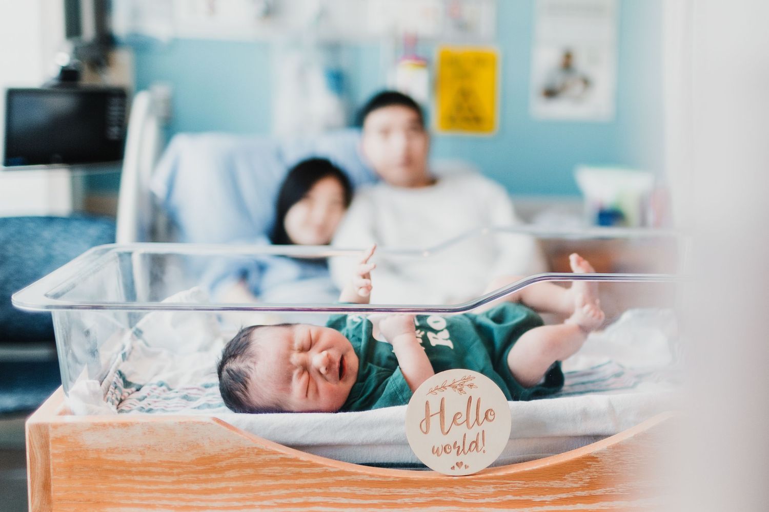 Newborn baby in a nursery hospital room with medical equipment.