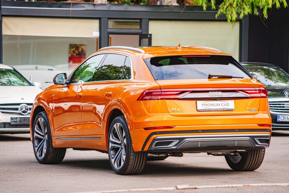 Side profile of an orange Audi Q8 Sportback showcasing its coupe-like roofline.