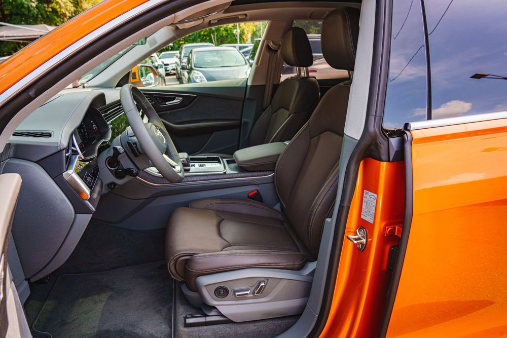 Orange vehicle's front seat interior showing power-adjustable leather seats.