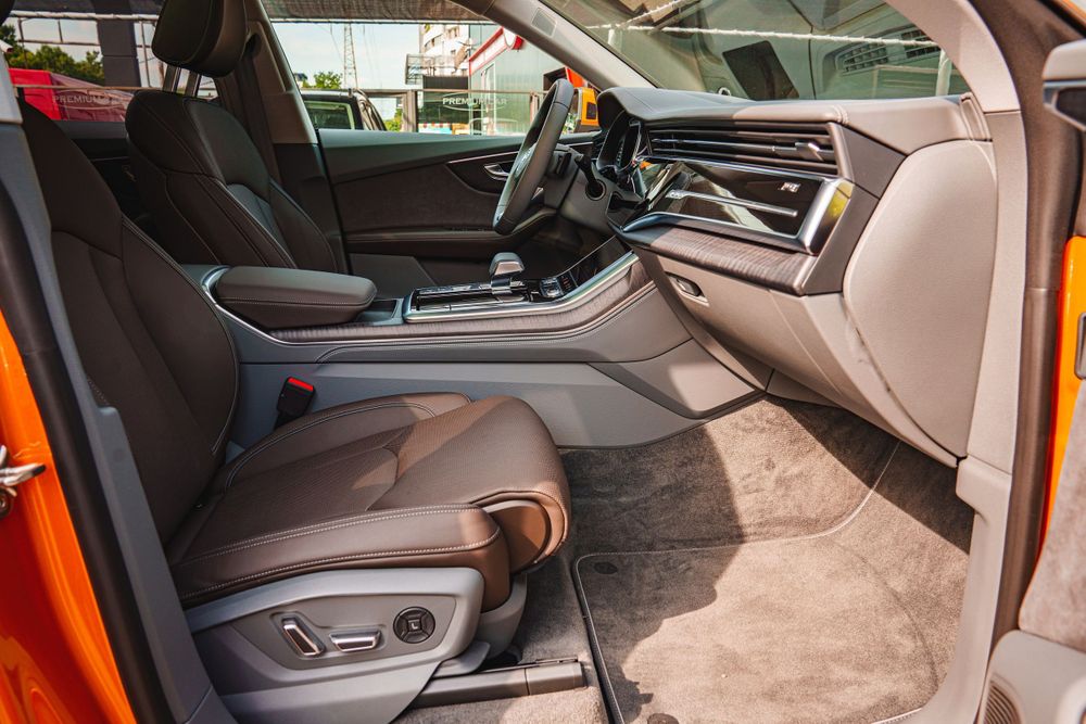 Power-adjustable front seats in brown leather with electronic controls visible.