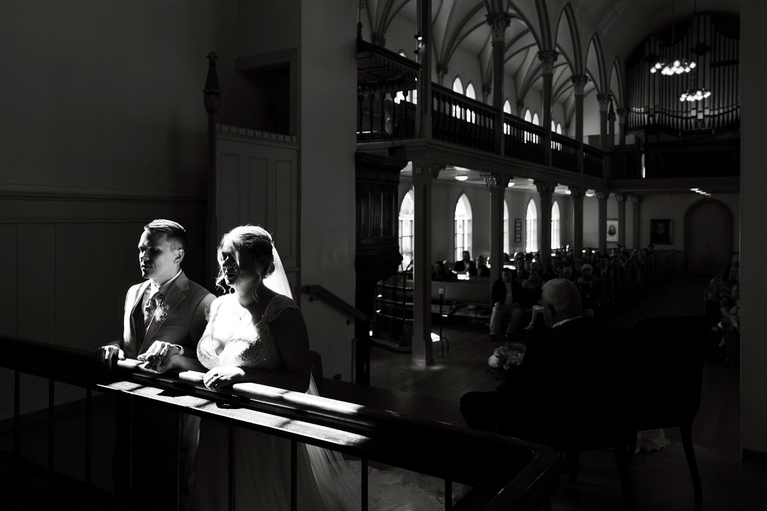 Black and white photo of sunlit church interior with people sitting in pews.