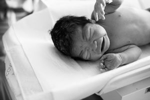 Newborn baby boy being weighed at hospital after birth.