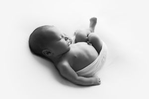 Baby boy backlit showing profile of his face in a white wrap.