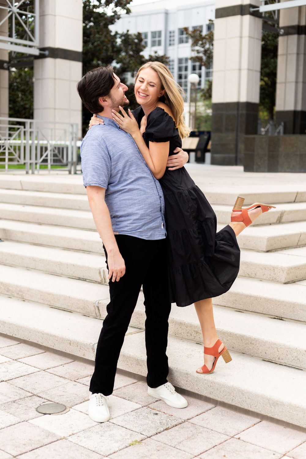 Happy couple sharing romantic moment on marble steps of modern building.