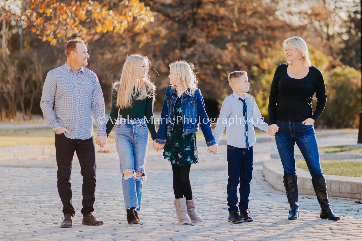 Golden light streams behind this stylish family holding hands and walking together.