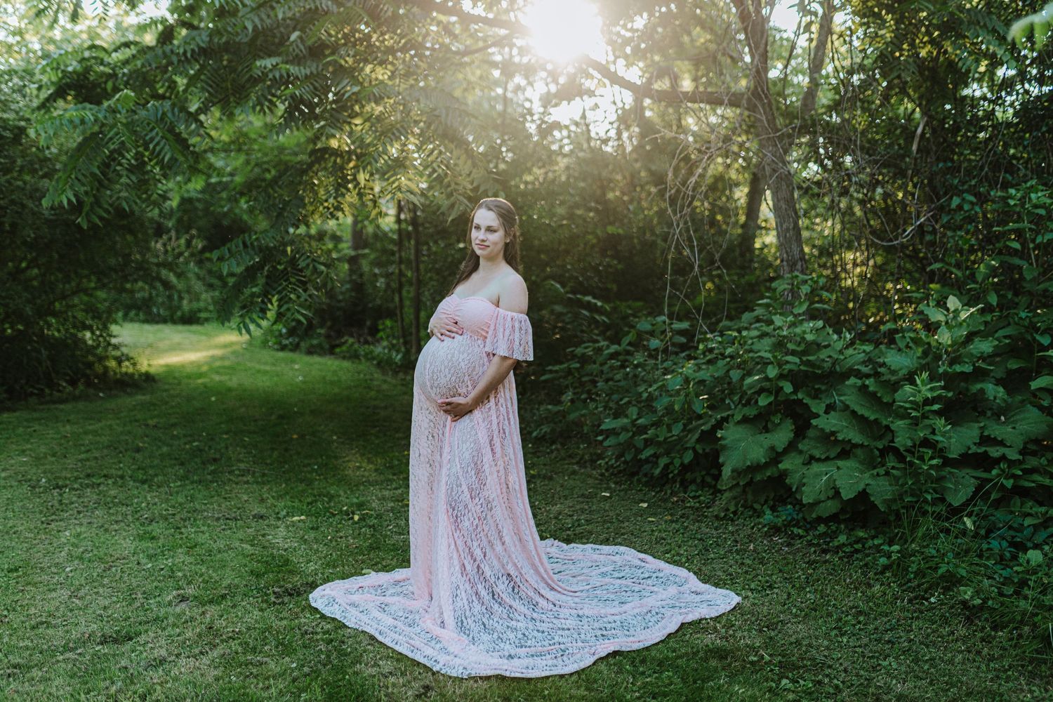 Woman stands in maternity gown for her photo session in a copse of trees in Fredericksburg, PA.
