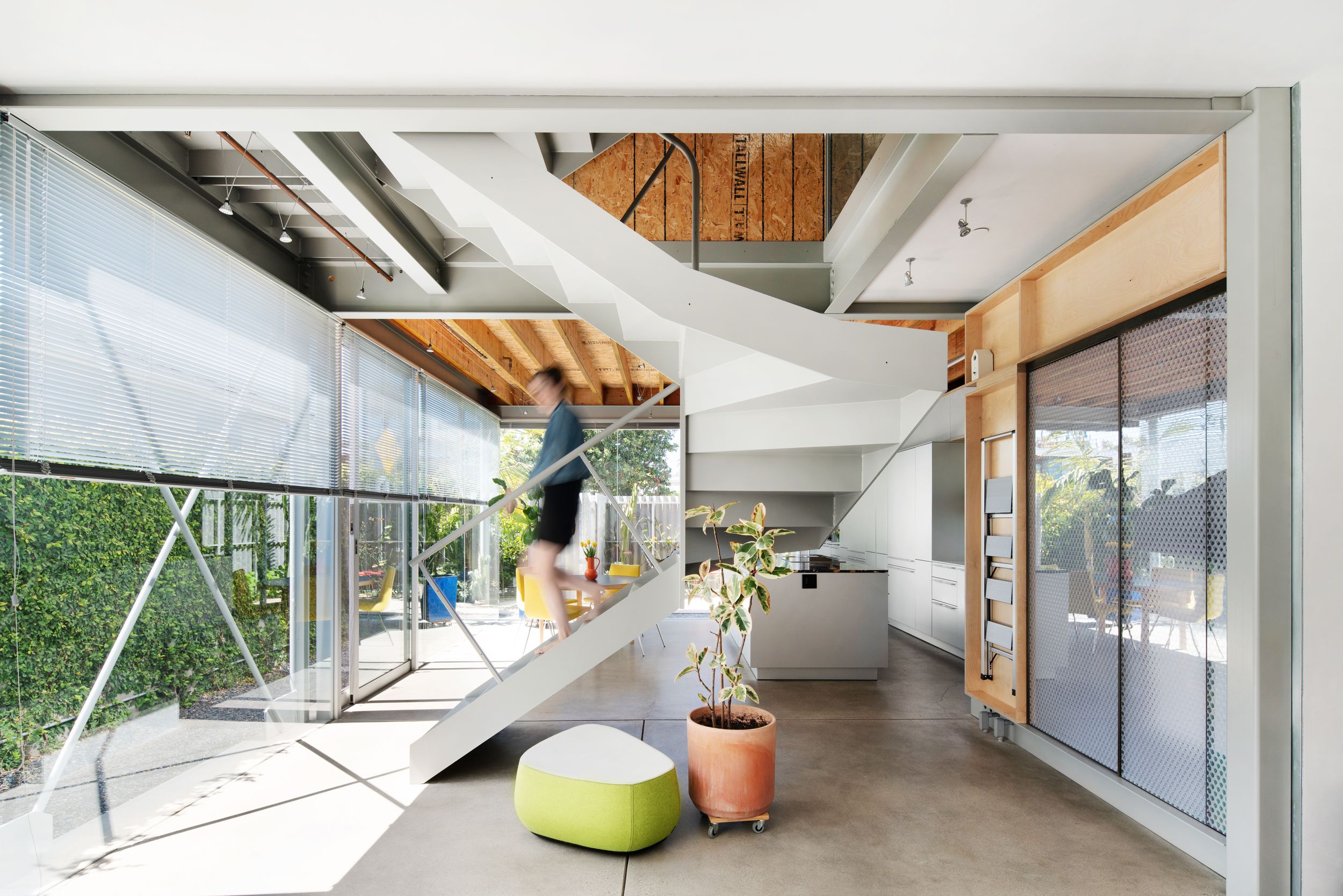 Modern interior space with angular white stairs and bright green accent furniture.