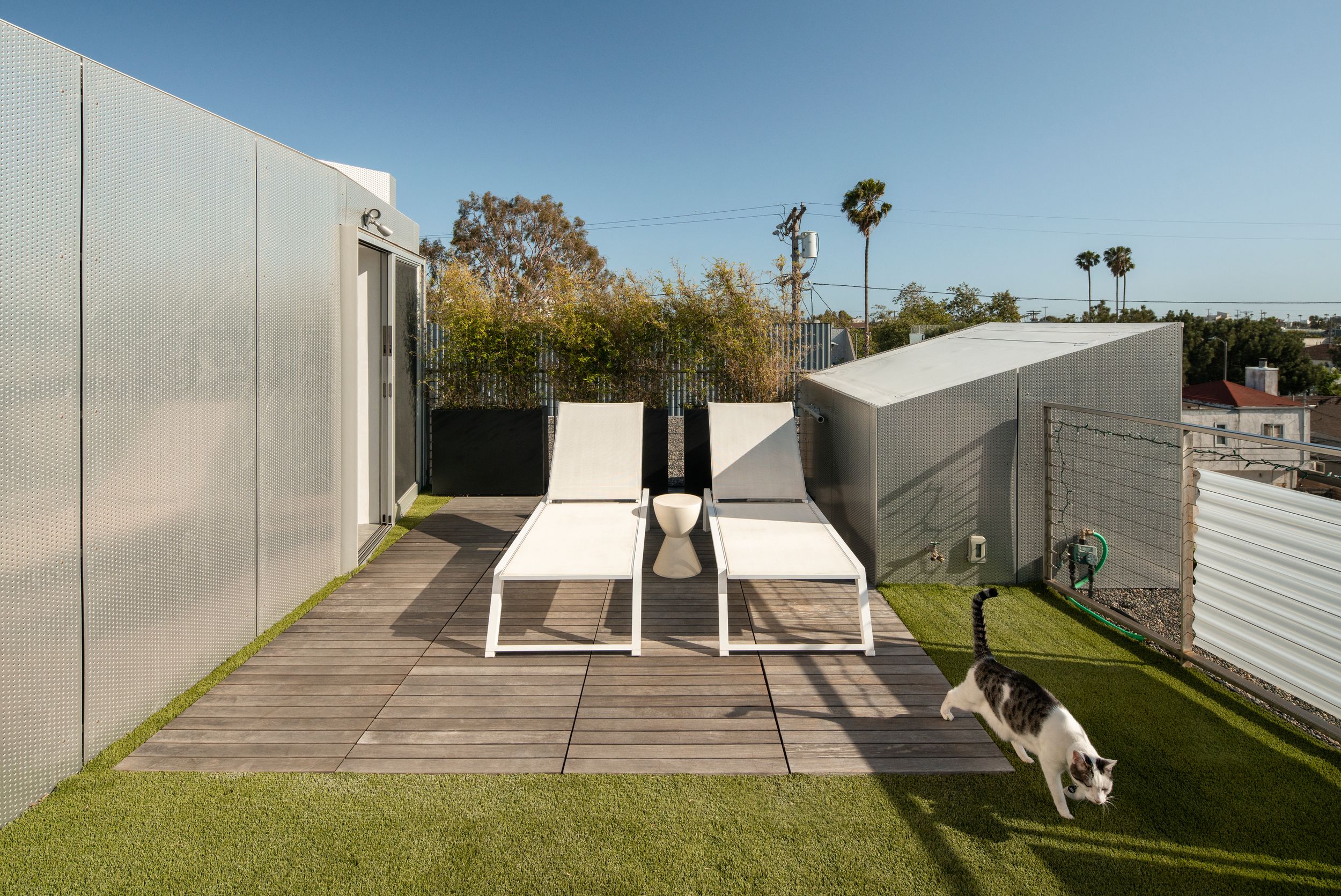 Rooftop deck with white lounge chairs and artificial grass offering a contemporary outdoor living space.