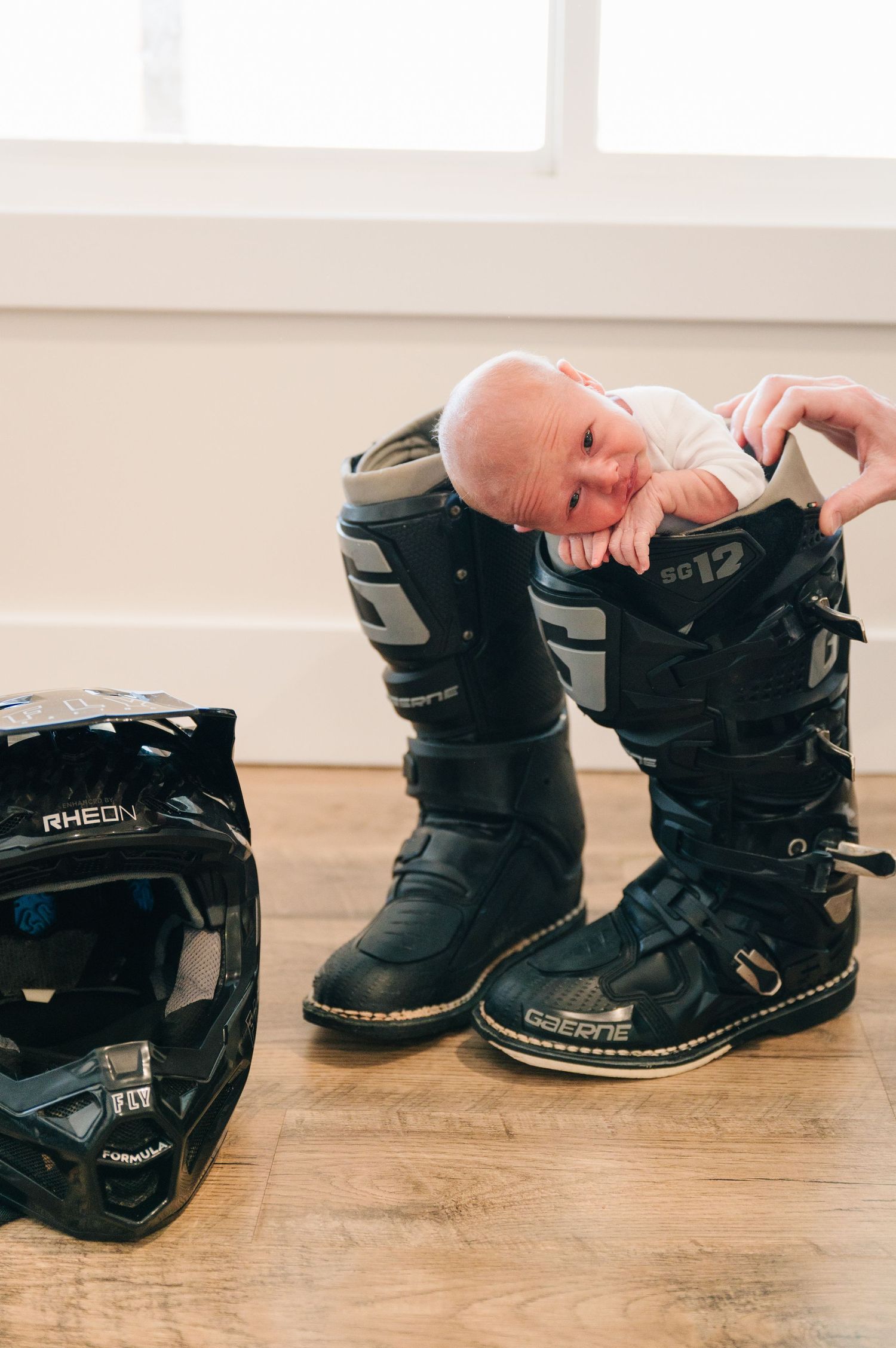 Creative newborn photo with baby nestled in black motorcycle boots.