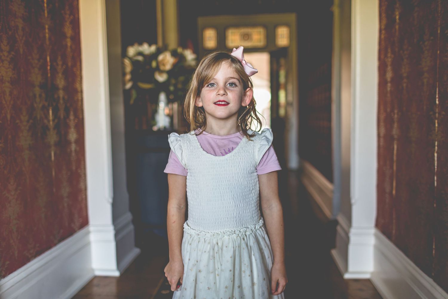 Young girl in a light dress standing in an elegant hallway.