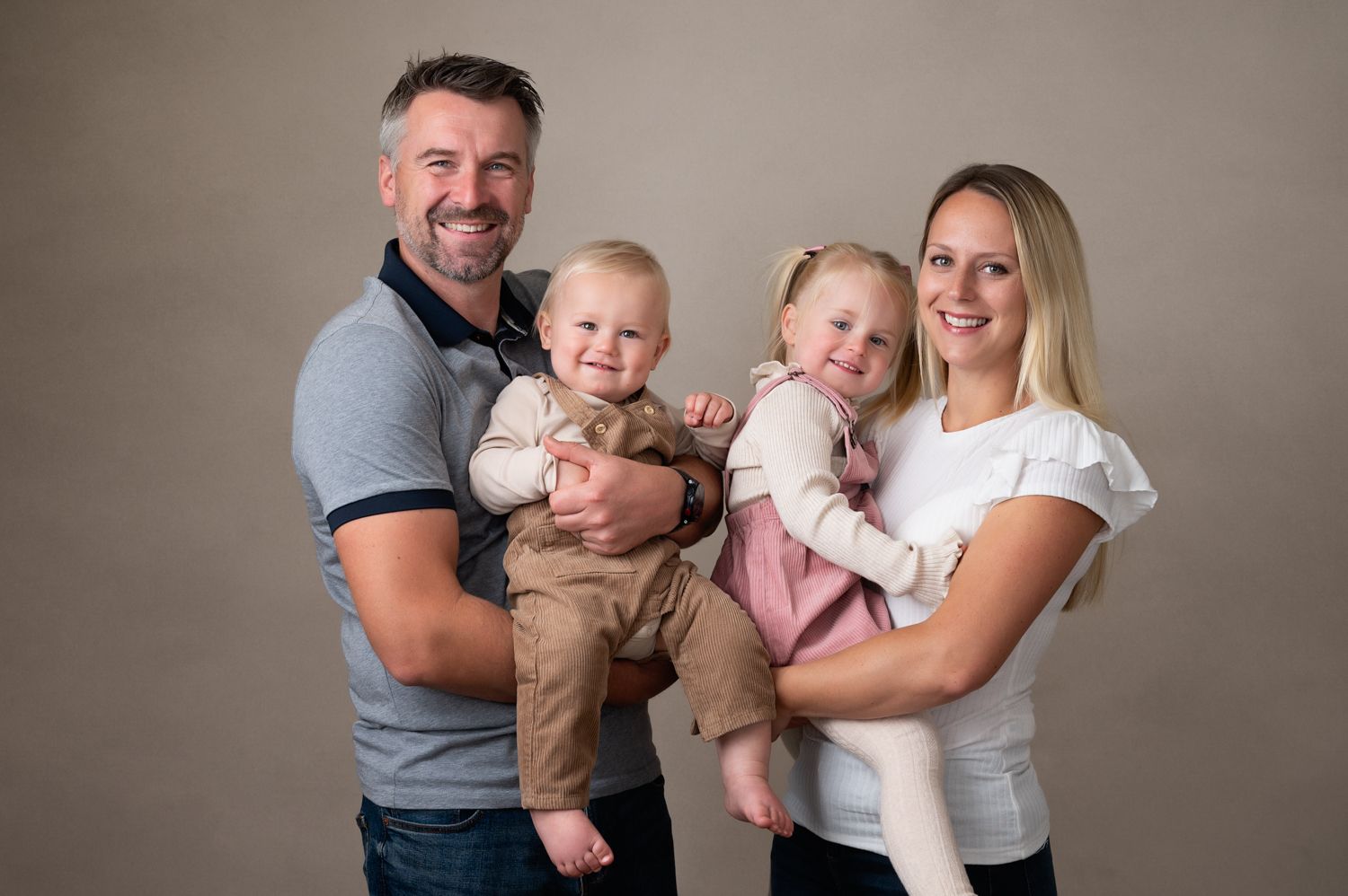 Studio family portrait with children against neutral background.