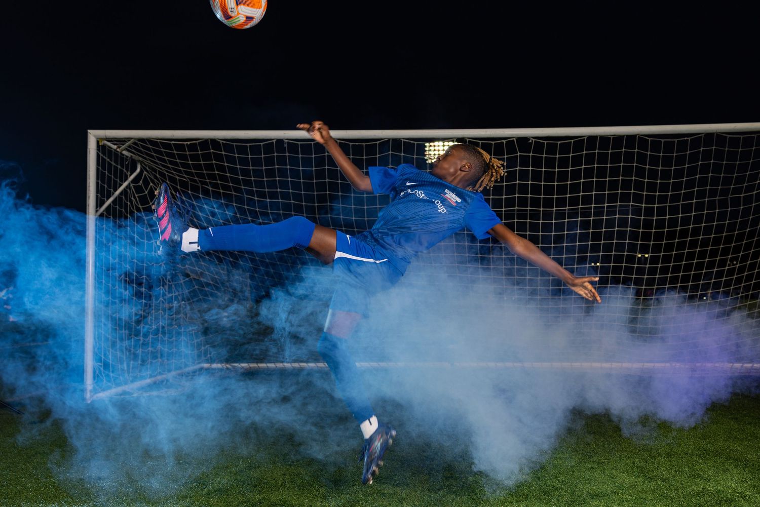Soccer action sequence with blue smoke effects near the goal during an intense match.