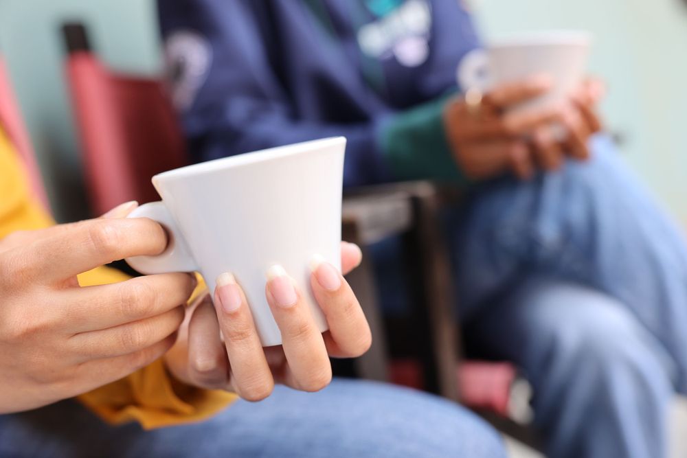Hands holding white coffee cups in a casual gathering.