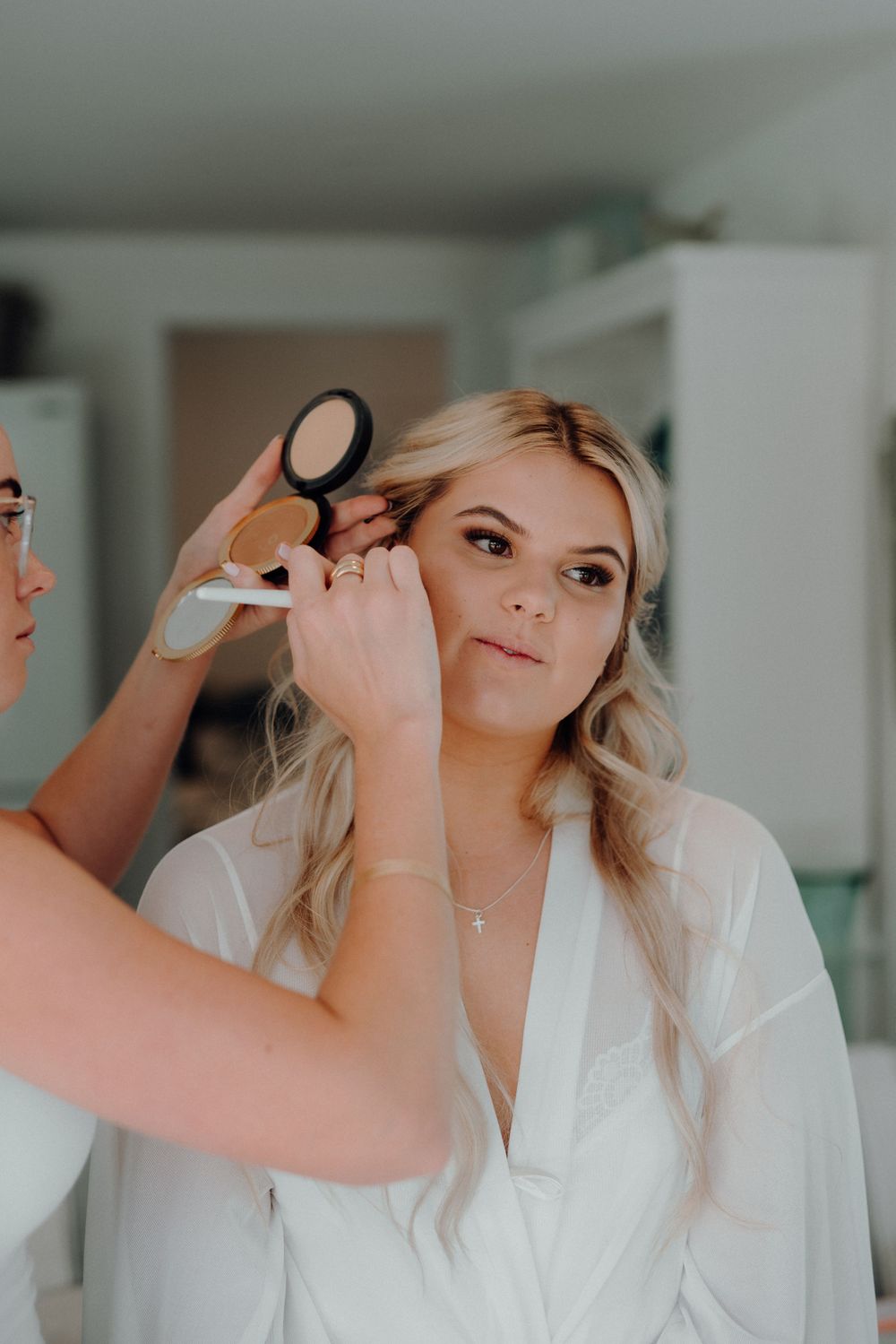 Final touches being applied during bridal preparation in white room.